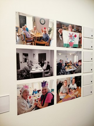 a set of six photos in a grid on a white wall in a gallery. They show members of the Creative Age projects showing off their craft work.